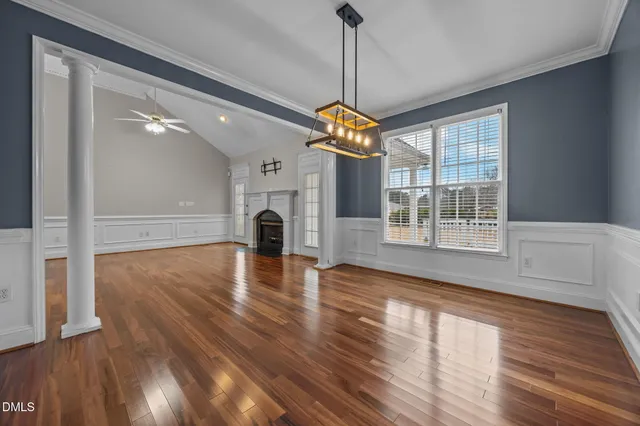 a view of an empty room with wooden floor fireplace and a window