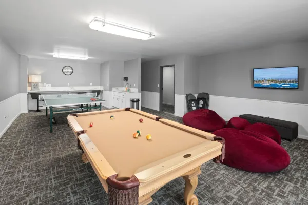 a room with a sink pool table and chairs