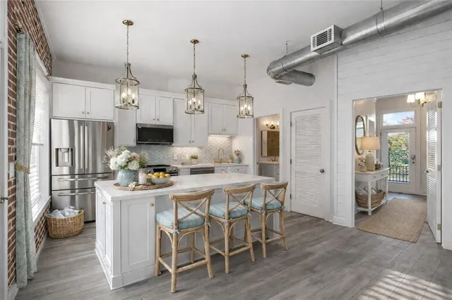 a kitchen with stainless steel appliances kitchen island granite countertop a table chairs and a wooden floor