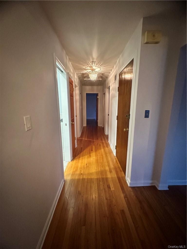 545 Pelham Road New Rochelle, NY 10805 - Photo 11 of 25 a view of a hallway with wooden floor and a chandelier