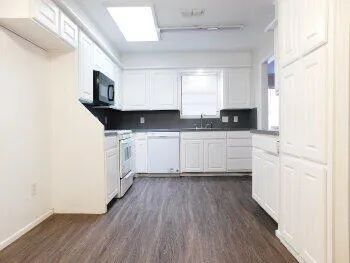 a kitchen with granite countertop a sink cabinets and wooden floor