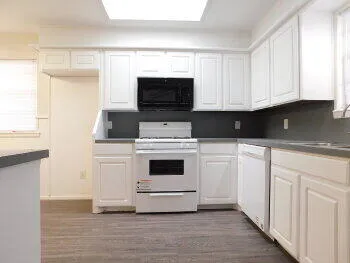 a white kitchen with a sink and a stove top oven