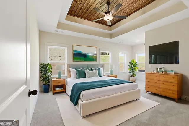 a spacious bedroom with a bed and a flat screen tv