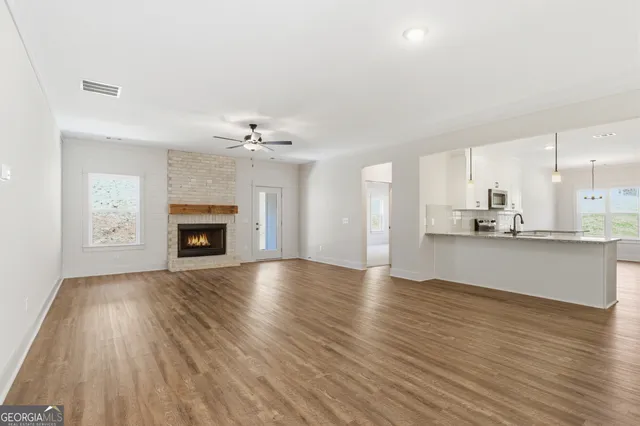 a view of an empty room with wooden floor fireplace and a window