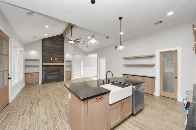 a large kitchen with kitchen island a large counter top space a sink stainless steel appliances and cabinets