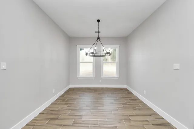 a view of a room with wooden floor table and chairs