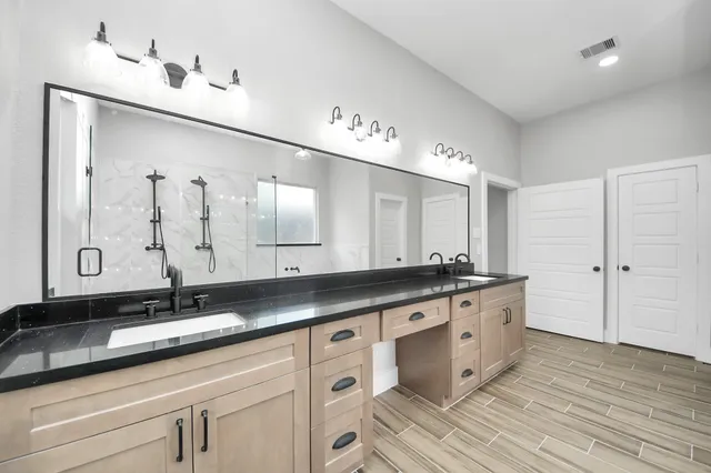 a spacious bathroom with a double vanity sink a mirror and a bathtub