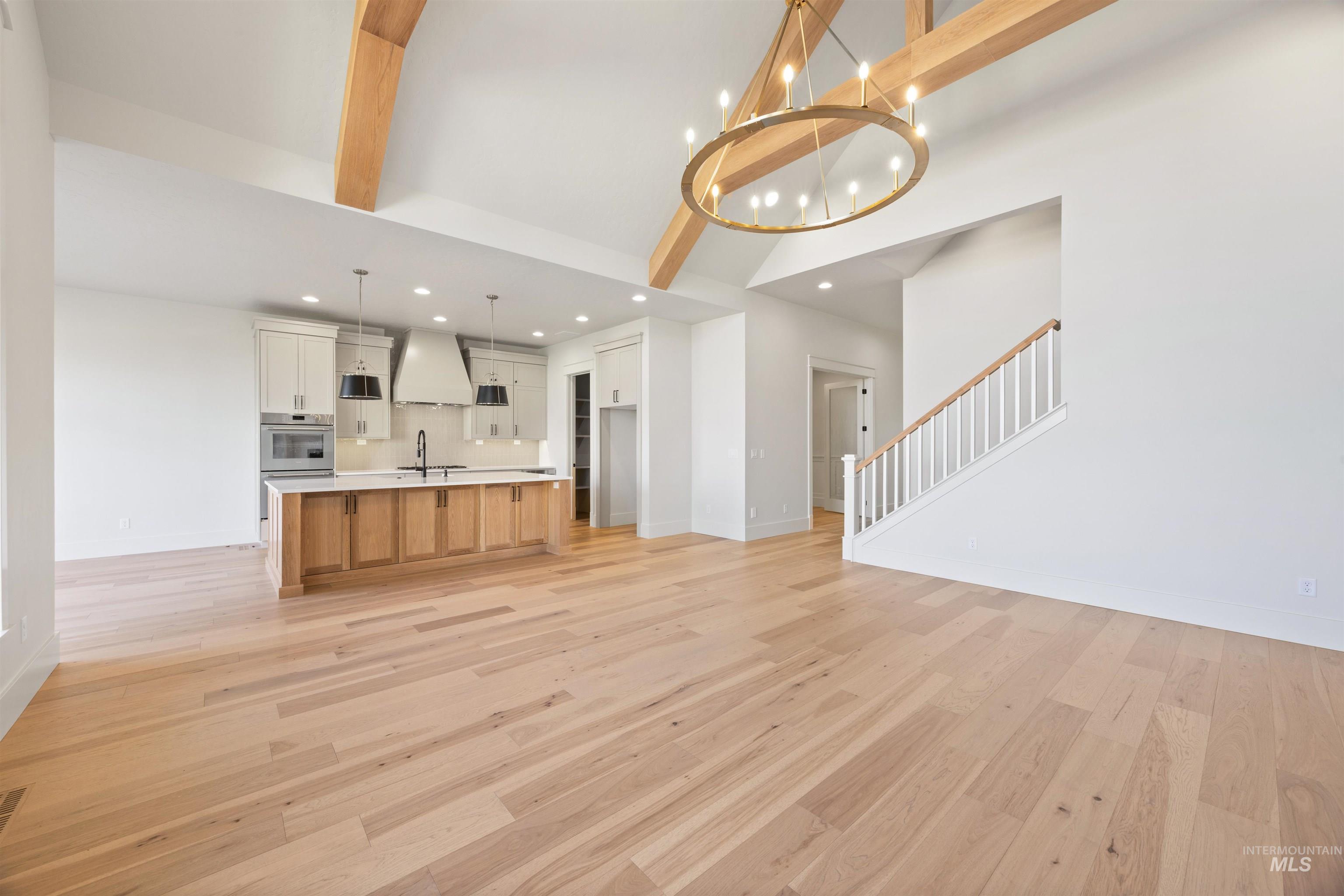 1090 East Crescendo Street Meridian, ID 83642 - Photo 11 of 50 Unfurnished living room with suspended lighting, light wood-style flooring, and vaulted ceiling