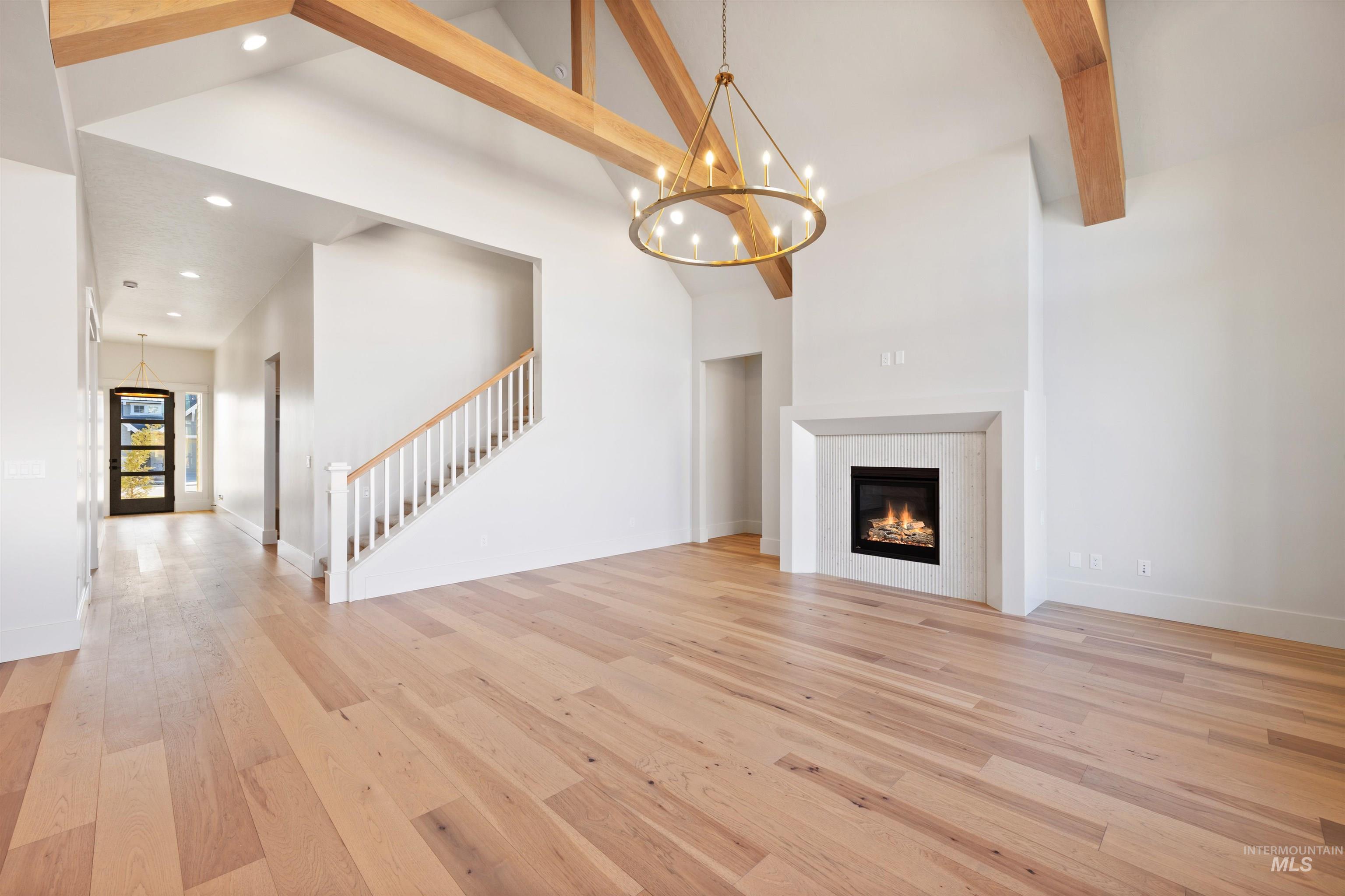 1090 East Crescendo Street Meridian, ID 83642 - Photo 12 of 50 Unfurnished living room with hanging lights, light wood finished floors, a glass covered fireplace, and vaulted ceiling