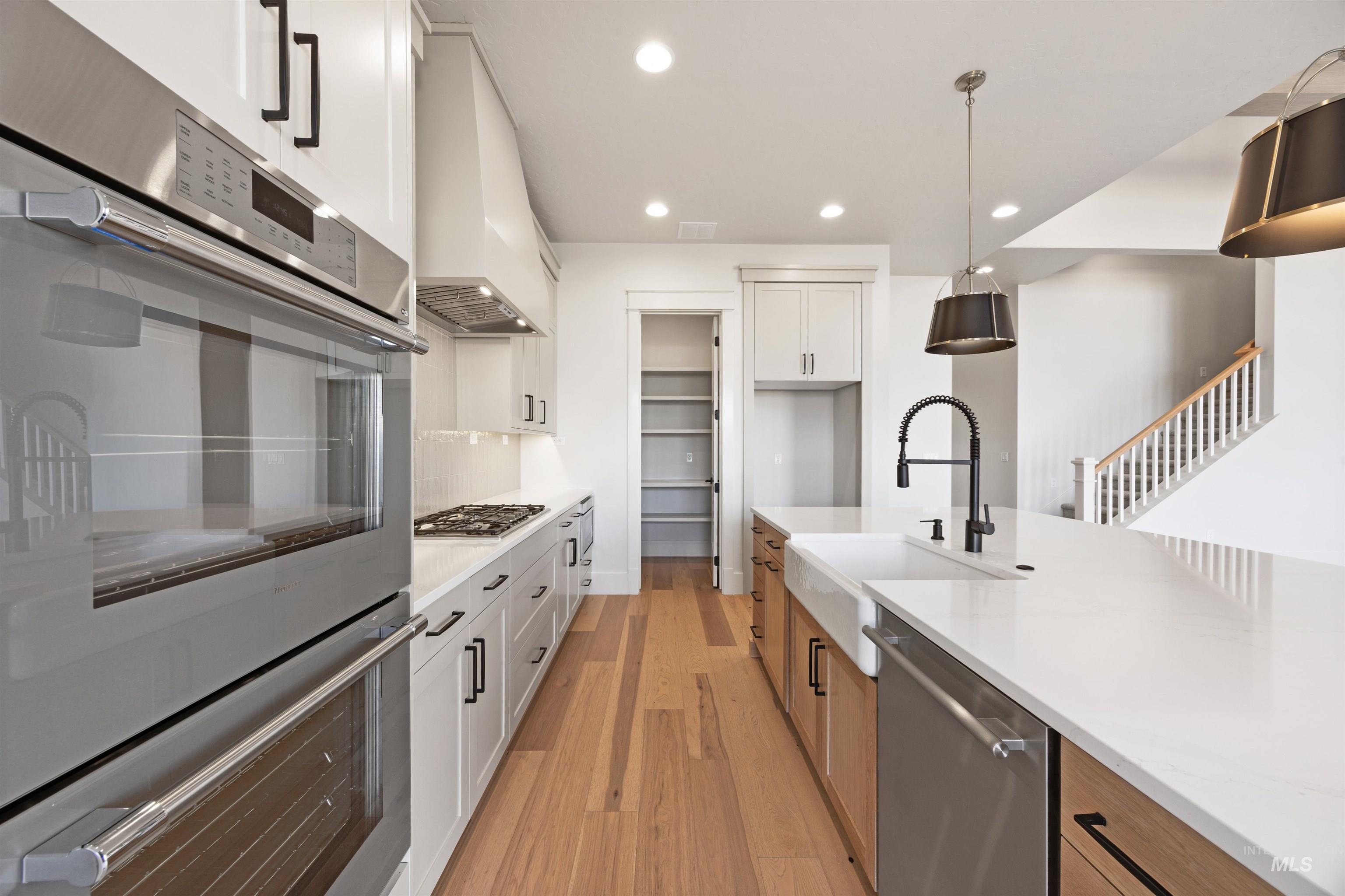 1090 East Crescendo Street Meridian, ID 83642 - Photo 15 of 50 Kitchen featuring stainless steel appliances, dual tone cabinets, light wood finished floors, light stone countertops, and hanging light fixtures