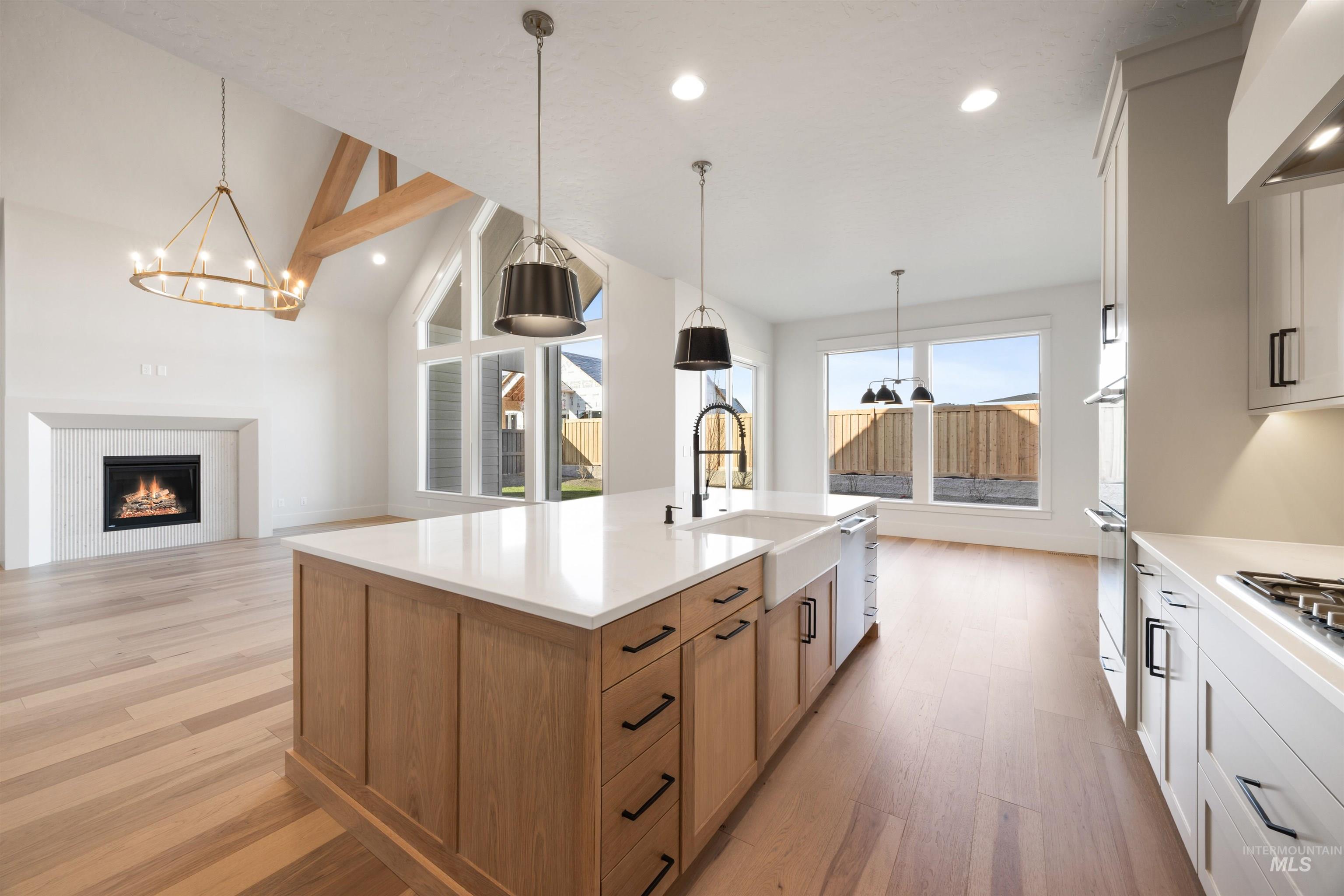 1090 East Crescendo Street Meridian, ID 83642 - Photo 50 of 50 Kitchen with two tone color scheme, a lit fireplace, light wood-style floors, open floor plan, and exhaust hood