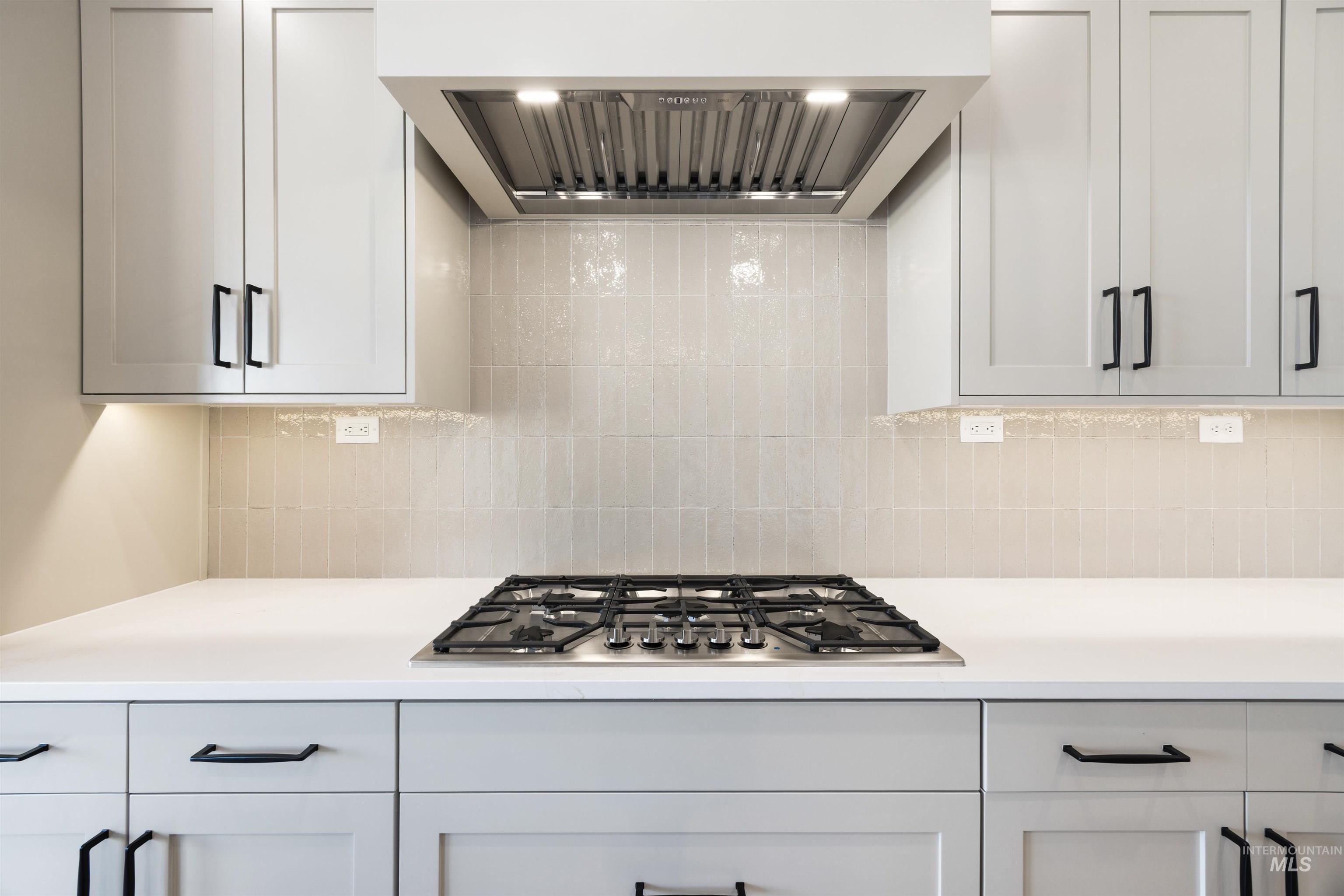 1090 East Crescendo Street Meridian, ID 83642 - Photo 24 of 50 Kitchen featuring extractor fan, stainless steel gas stovetop, white cabinets, and backsplash
