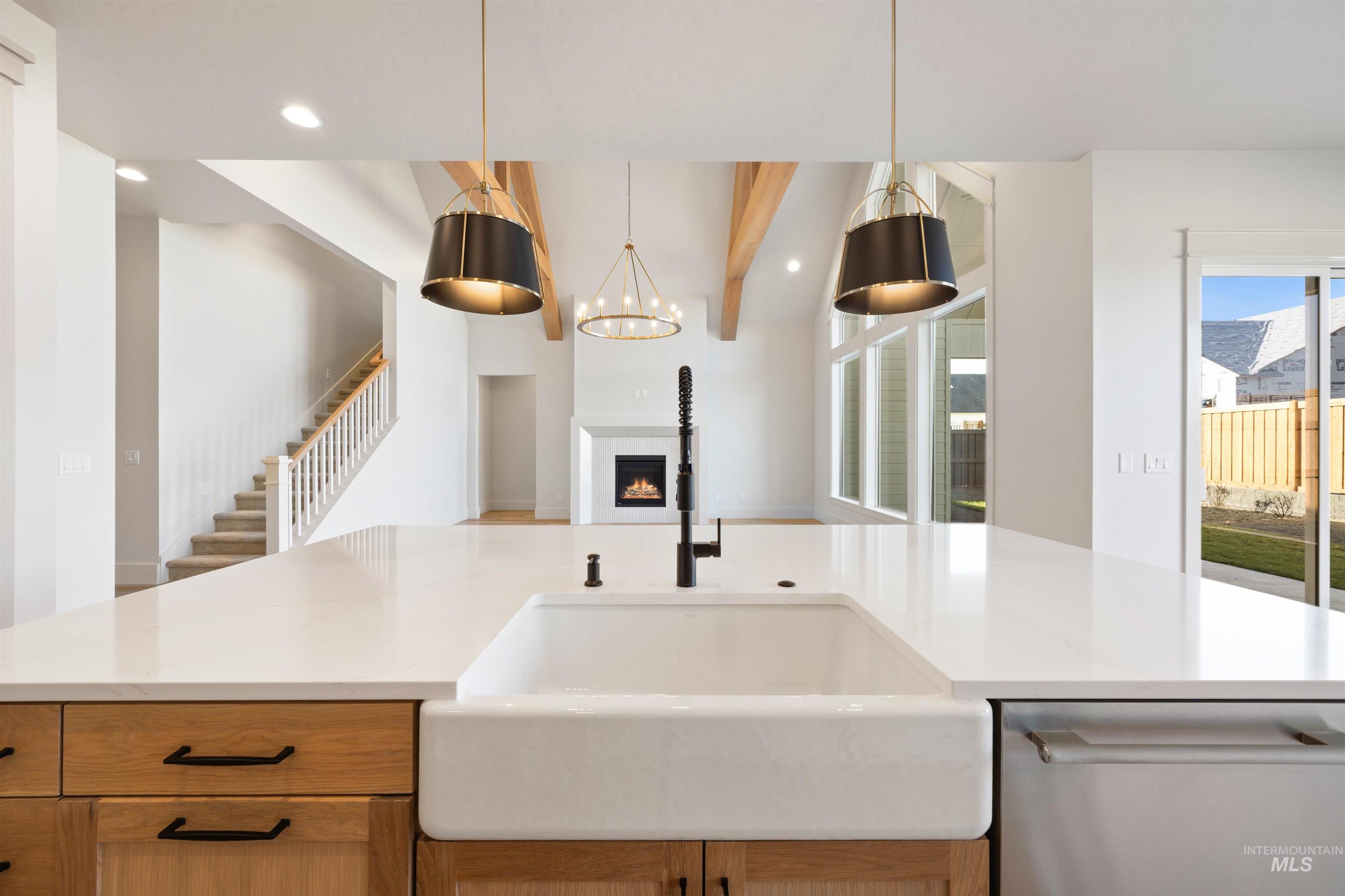 1090 East Crescendo Street Meridian, ID 83642 - Photo 25 of 50 Kitchen featuring a lit fireplace, stainless steel dishwasher, light stone counters, beamed ceiling, and healthy amount of natural light