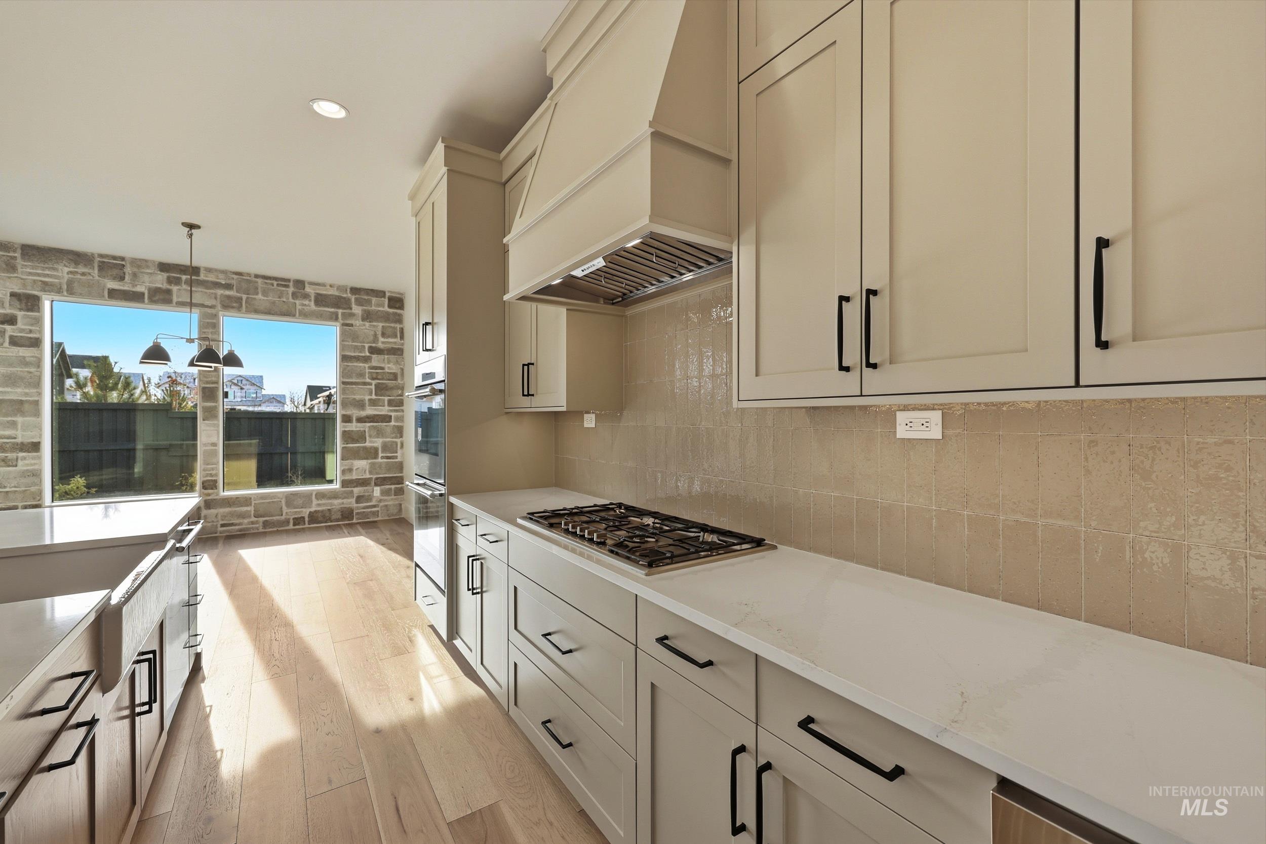 1090 East Crescendo Street Meridian, ID 83642 - Photo 8 of 43 Kitchen with decorative light fixtures, light wood finished floors, light stone countertops, recessed lighting, and premium range hood