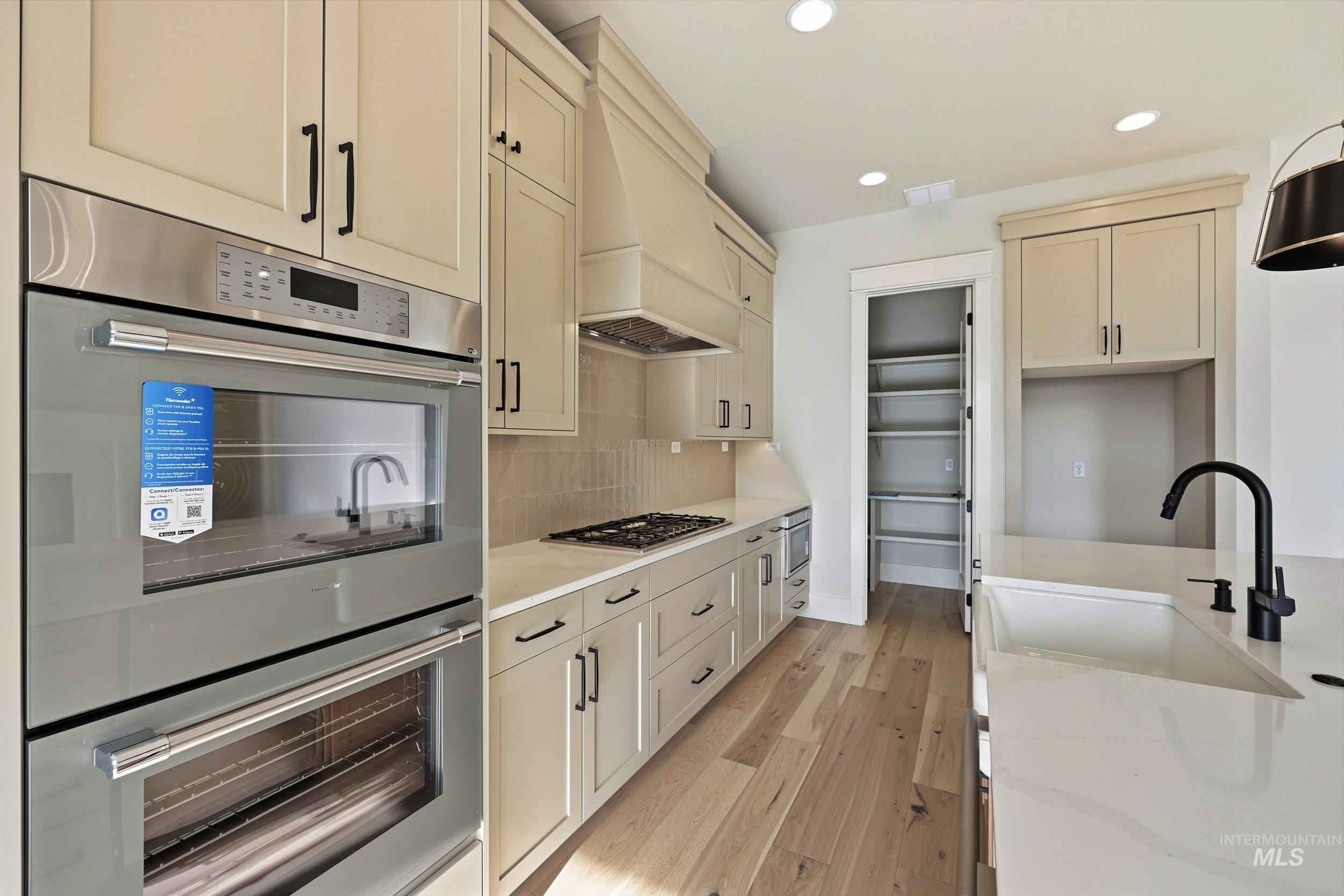 1090 East Crescendo Street Meridian, ID 83642 - Photo 9 of 43 Kitchen with appliances with stainless steel finishes, cream cabinets, recessed lighting, light wood-style flooring, and light stone counters
