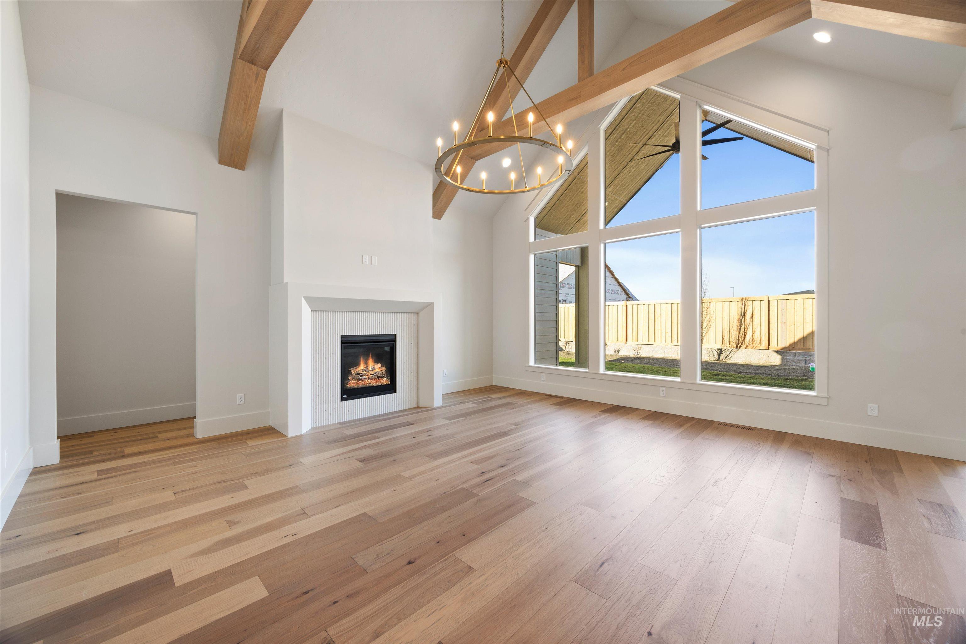 1090 East Crescendo Street Meridian, ID 83642 - Photo 10 of 50 Unfurnished living room with light wood-style floors, a glass covered fireplace, and hanging lights