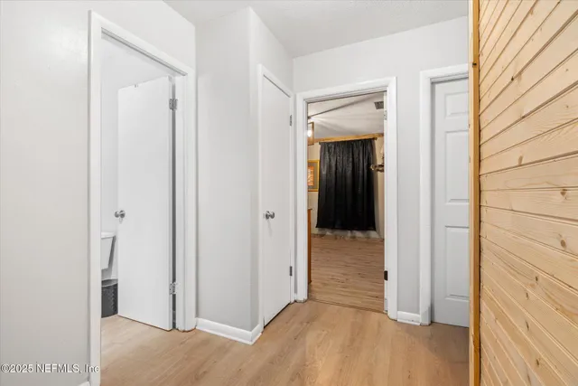 a view of a hallway with wooden floor and closet