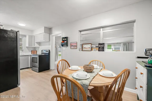 a kitchen with stainless steel appliances granite countertop a dining table chairs refrigerator and sink