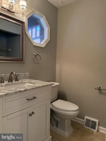 a bathroom with a granite countertop toilet sink and mirror