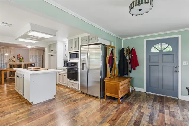 a kitchen with stainless steel appliances kitchen island granite countertop a refrigerator a stove and a sink with cabinets