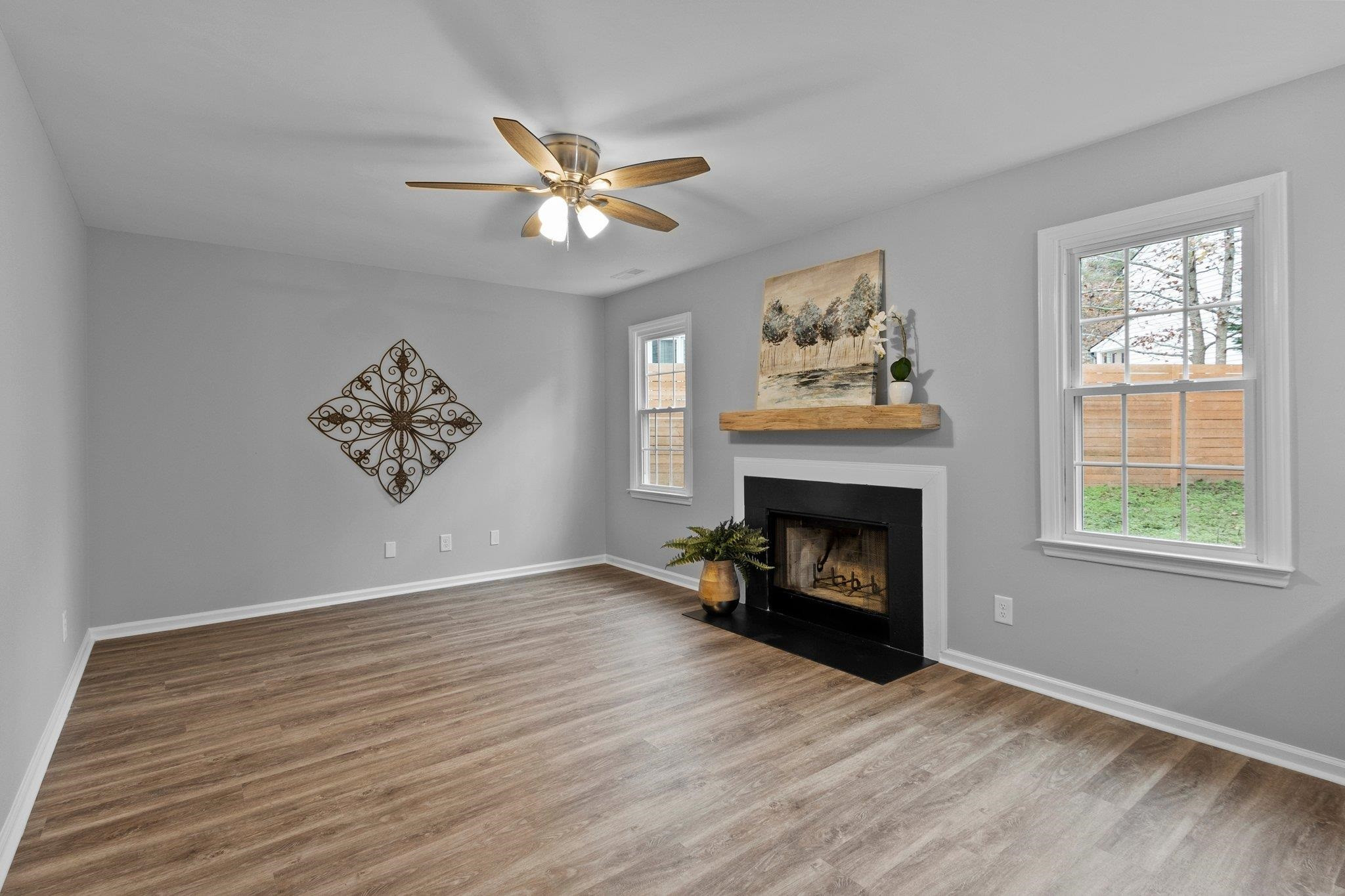 5616 Torness Court Raleigh, NC 27604 - Photo 12 of 37 Family Room has fireplace, two windows, LVP flooring, and ceiling fan. Family Room