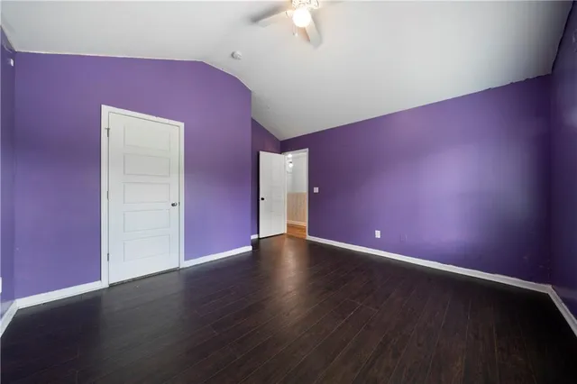 a view of an empty room with wooden floor and a ceiling fan