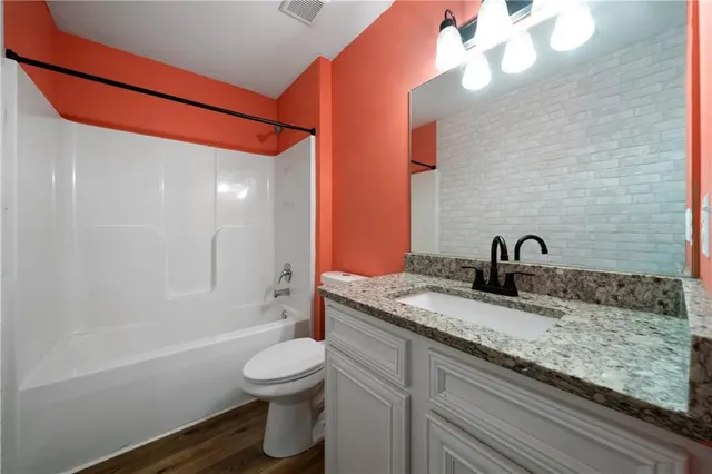 a bathroom with a granite countertop sink a toilet and shower