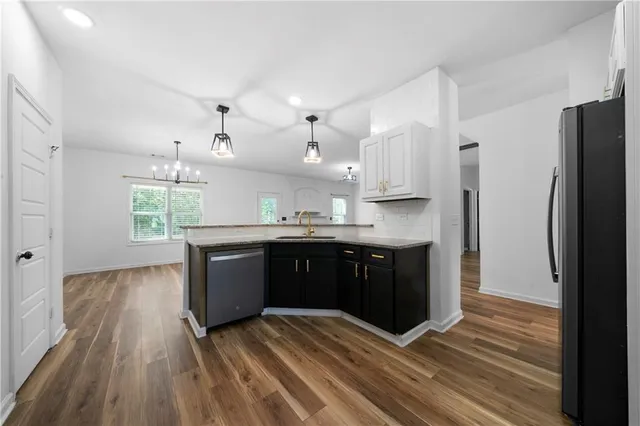 a kitchen with stainless steel appliances granite countertop a refrigerator a sink dishwasher a stove and white countertops with wooden floor