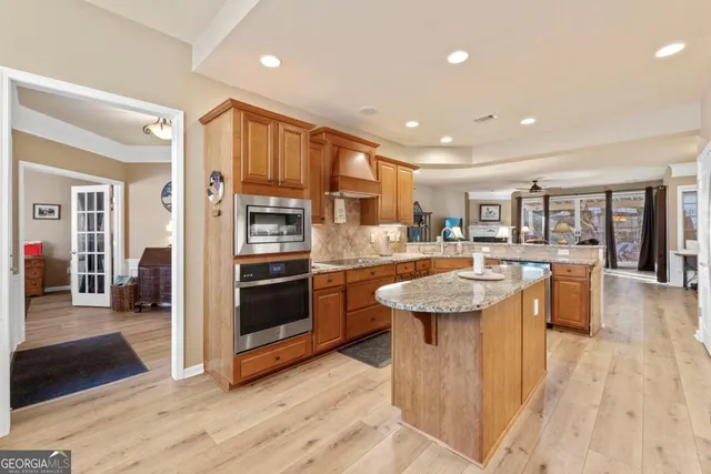 a large white dining hall with stainless steel appliances granite countertop a stove oven a table and chairs with wooden floor