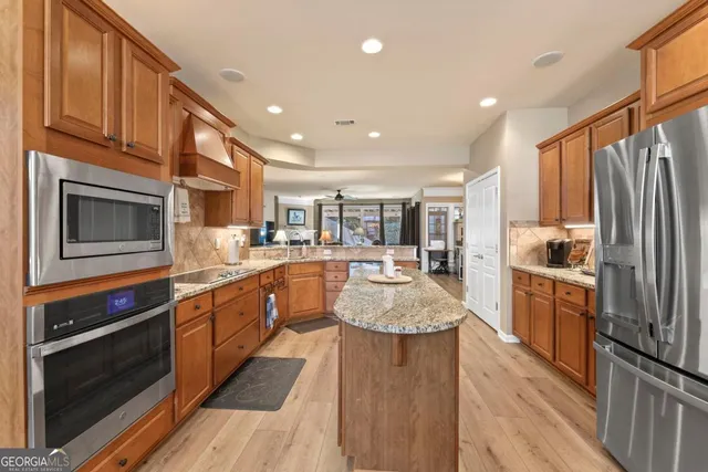 a kitchen with stainless steel appliances granite countertop a refrigerator a stove top oven a sink dishwasher and wooden cabinets with wooden floor