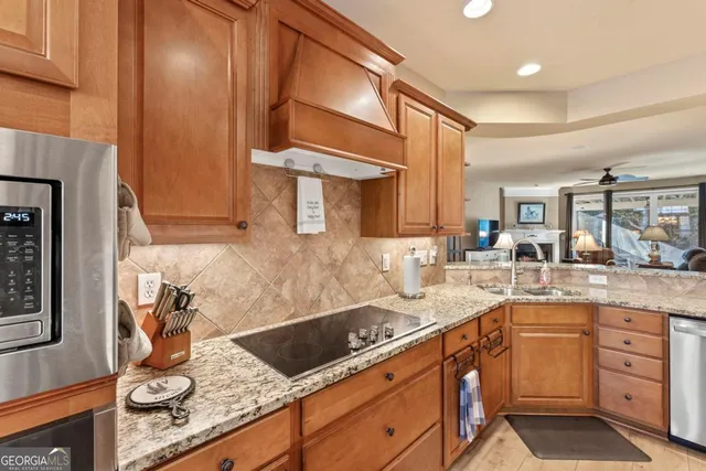 a kitchen with stainless steel appliances granite countertop sink stove refrigerator dining table and chairs