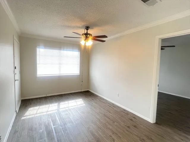 an empty room with wooden floor chandelier fan and windows