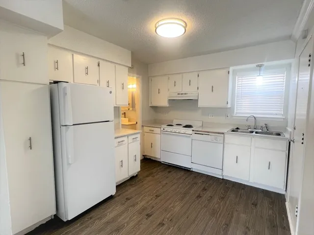 a kitchen with granite countertop white cabinets and white appliances