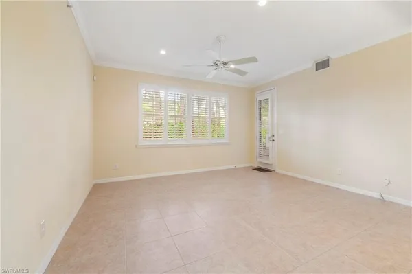 an empty room with windows and chandelier fan