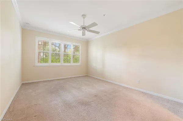 an empty room with a window and ceiling fan