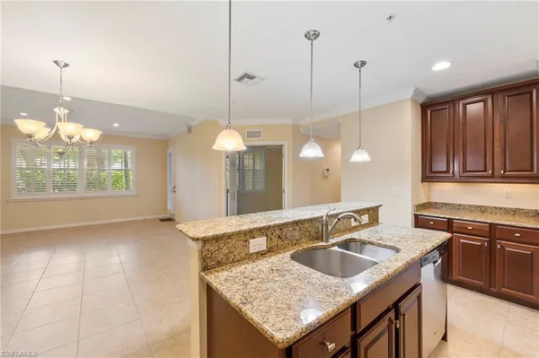 a kitchen with a sink a faucet a chandelier and living room view