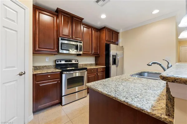a kitchen with granite countertop wooden cabinets a stove top oven and stainless steel appliances
