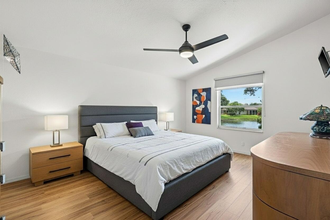 7370 Modena Drive Boynton Beach, FL 33437 - Photo 20 of 37 a bedroom with a large bed and a chandelier