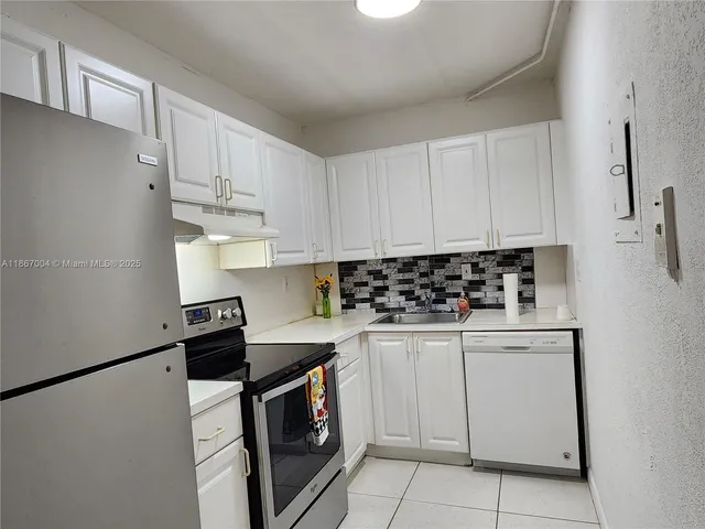 a kitchen with white cabinets and appliances