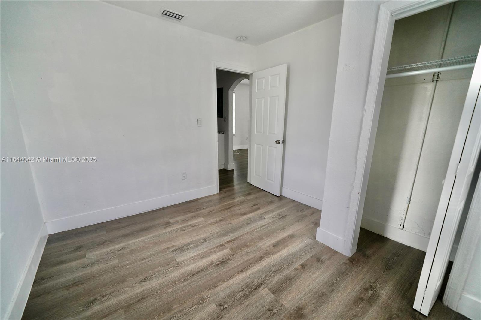 3376 Northwest 49th Street, Unit B Miami, FL 33142 - Photo 11 of 14 a view of an empty room with wooden floor and a window