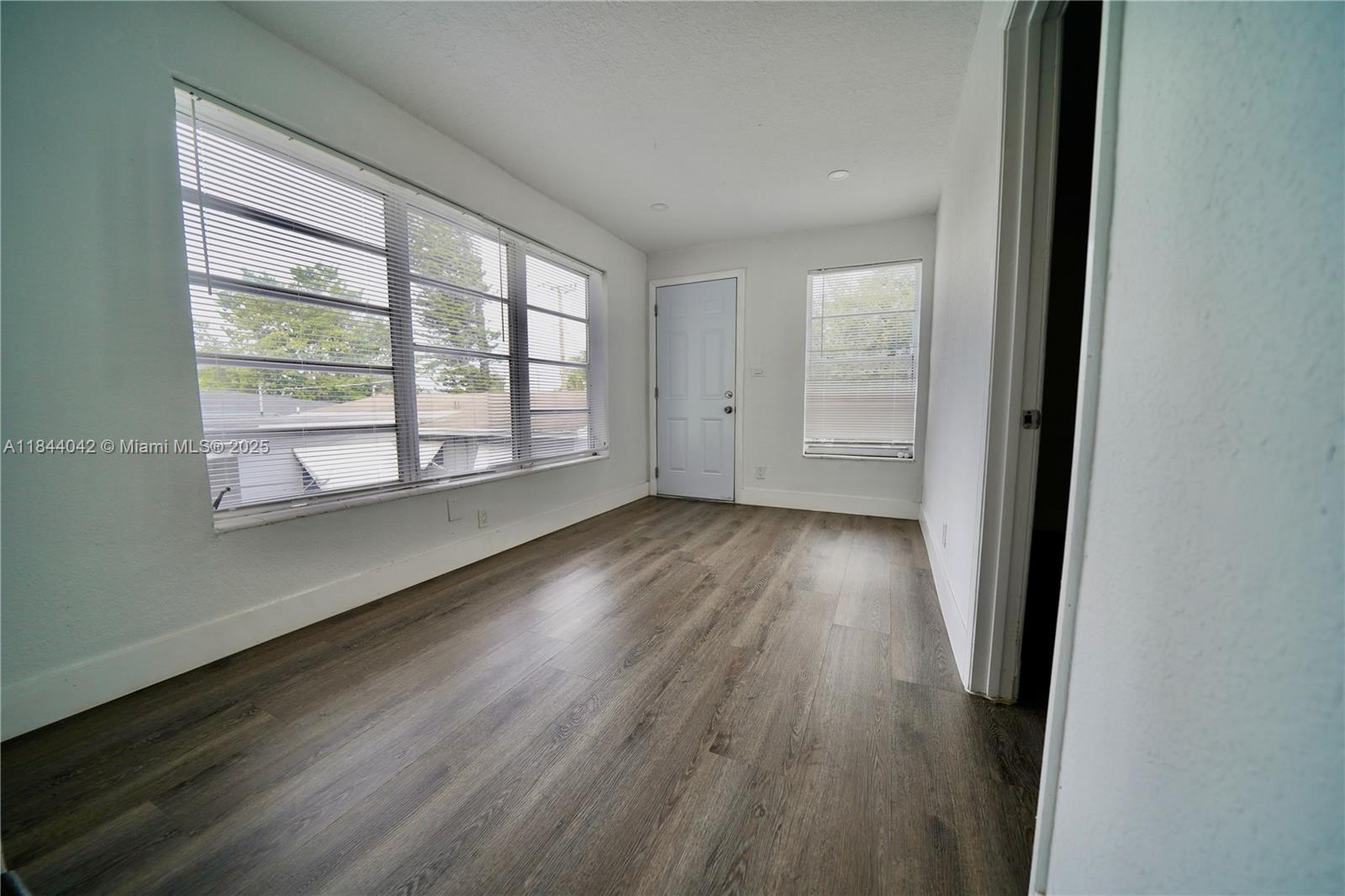 3376 Northwest 49th Street, Unit B Miami, FL 33142 - Photo 4 of 14 an empty room with wooden floor and windows