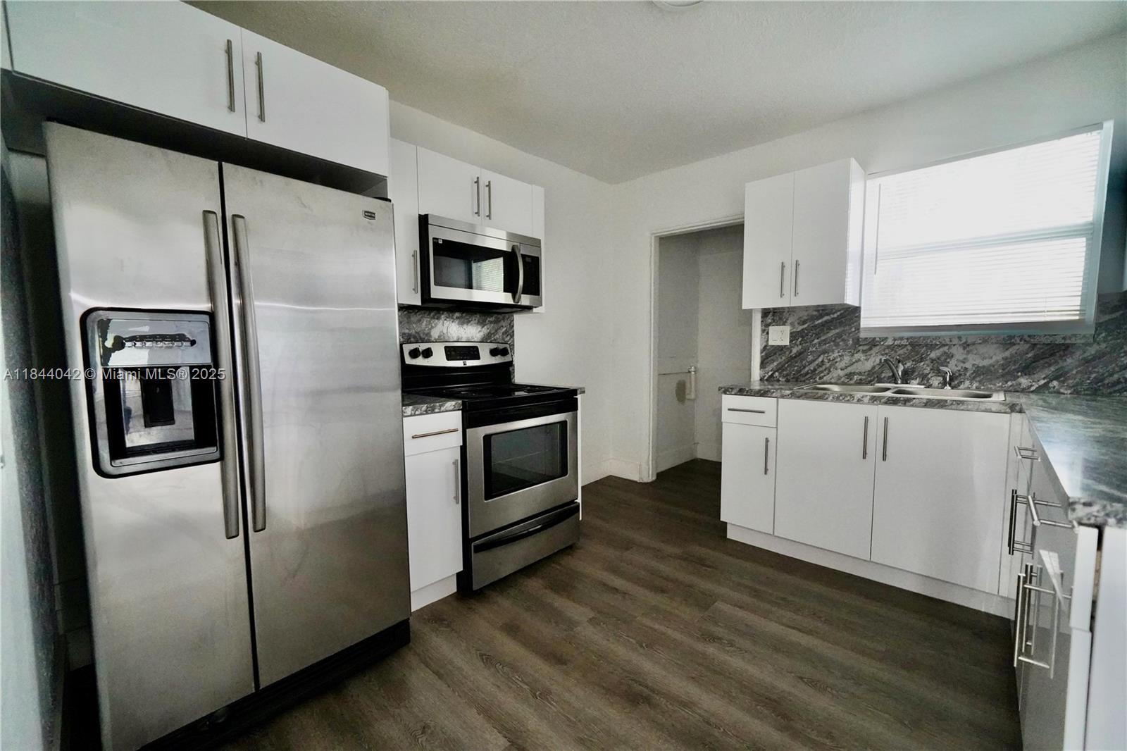 3376 Northwest 49th Street, Unit B Miami, FL 33142 - Photo 8 of 14 a kitchen with stainless steel appliances a refrigerator sink and microwave