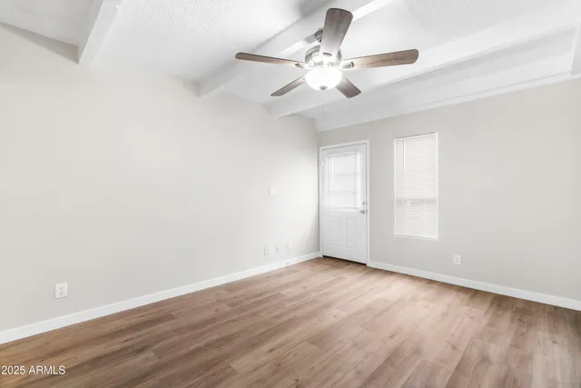 a view of an empty room with wooden floor and a window