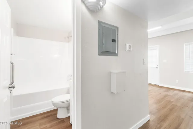 an empty room with wooden floor fan and windows