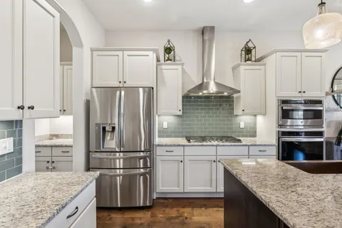 a kitchen with granite countertop a refrigerator sink and cabinets