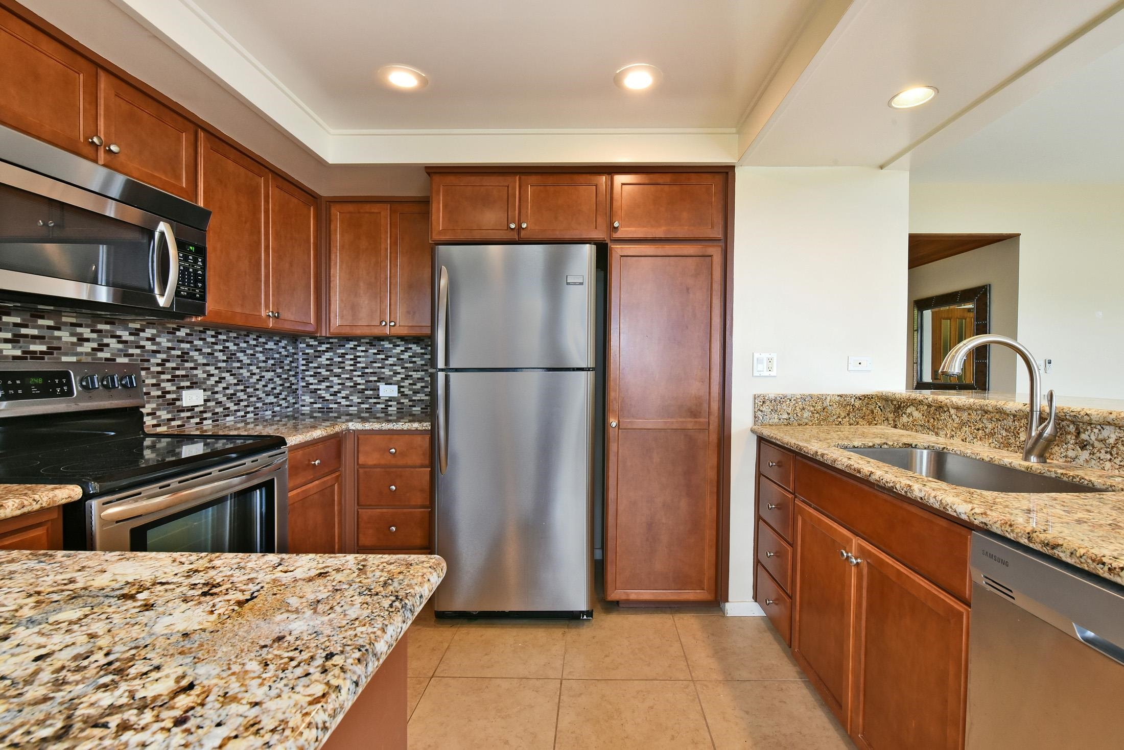 100 Ridge Road, Unit 101315 Lahaina, HI 96761 - Photo 11 of 23 a kitchen with stainless steel appliances granite countertop a refrigerator a sink and wooden cabinets