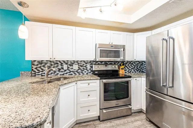 a kitchen with granite countertop a refrigerator stove and microwave