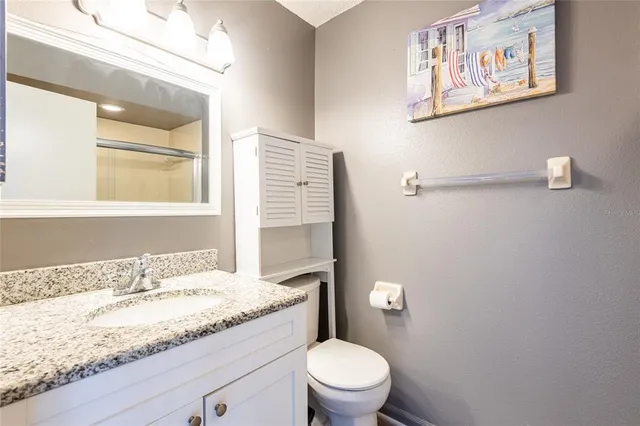 a bathroom with a granite countertop sink mirror vanity and toilet