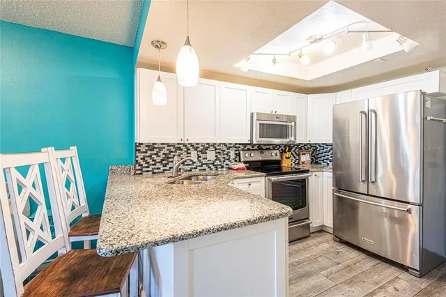 a kitchen with granite countertop a sink appliances and cabinets