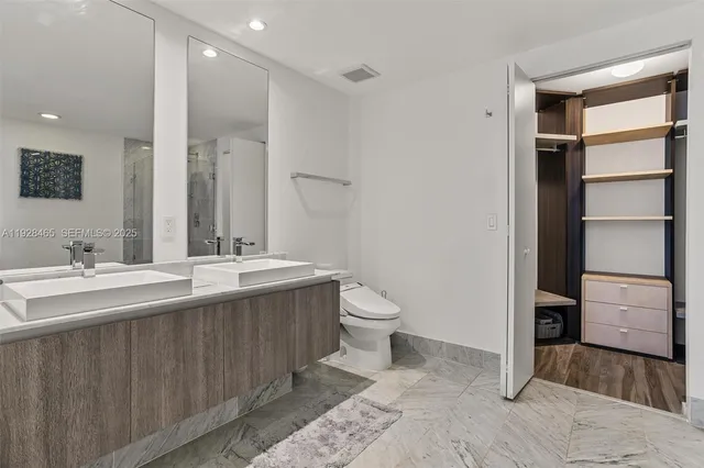a bathroom with a double vanity sink toilet and mirror